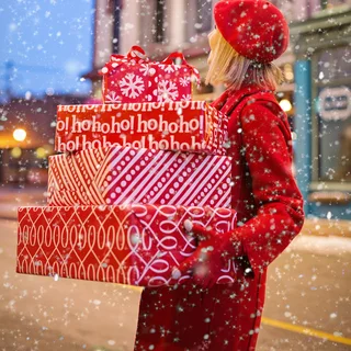 Someone carrying a stack of wrapped gifts in the snow
